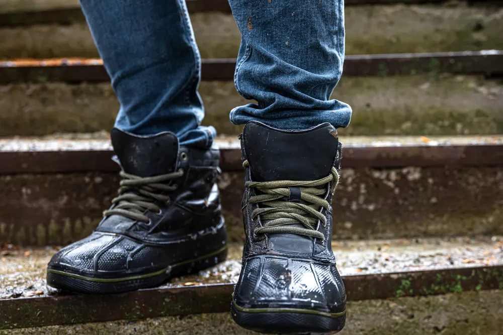 Herrenboots aus dunklem Leder mit Schnürung auf alten Steinstufen