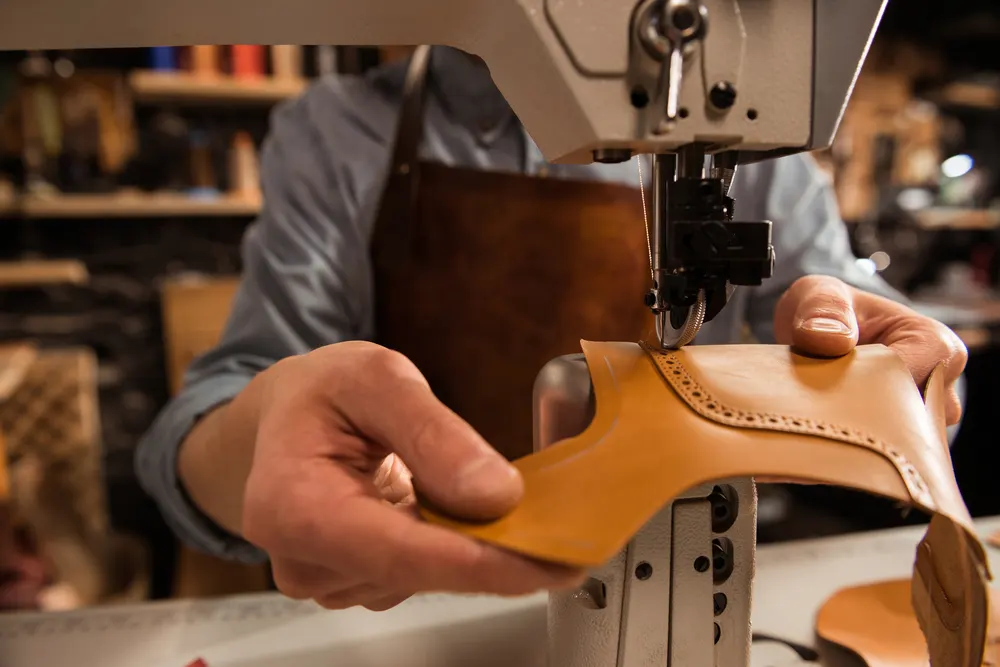 Schuhmacher näht an der Maschine Lederteile für einen Schuh