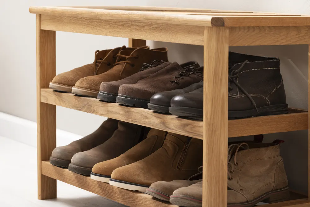 Holzregal mit braunen Lederschuhen und Stiefeln in einem Flur